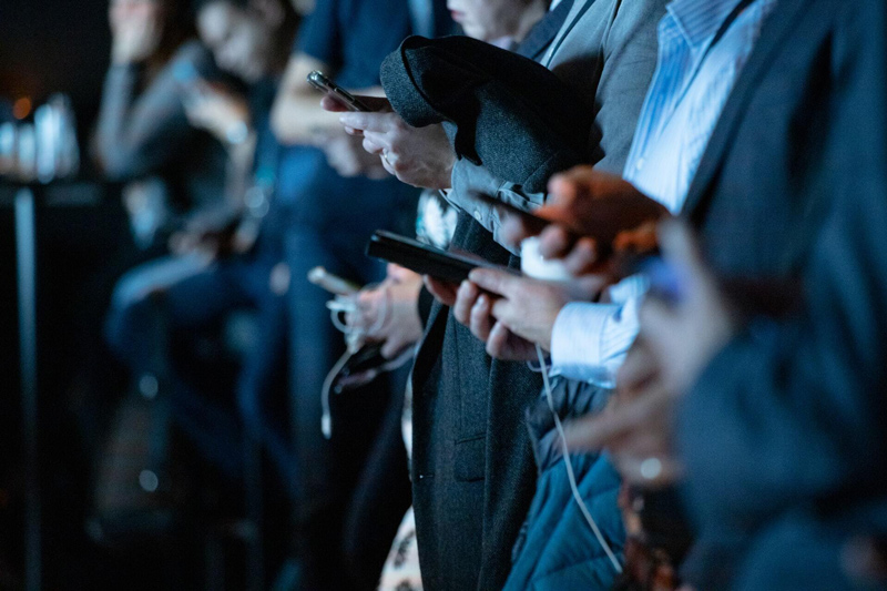 A row of people viewing real estate listings on their smartphones